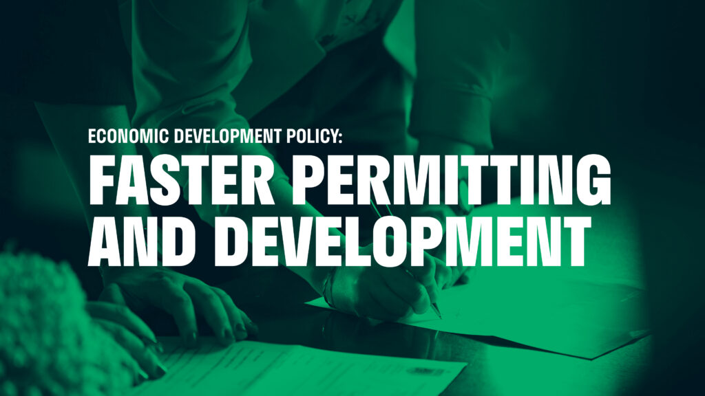 An image of hands holding pens writing on documents. The text on the image reads: "Economic Development Policy: Faster Permitting and Development"